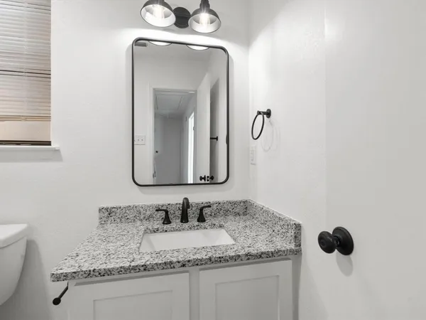 a bathroom with a granite countertop sink and a mirror