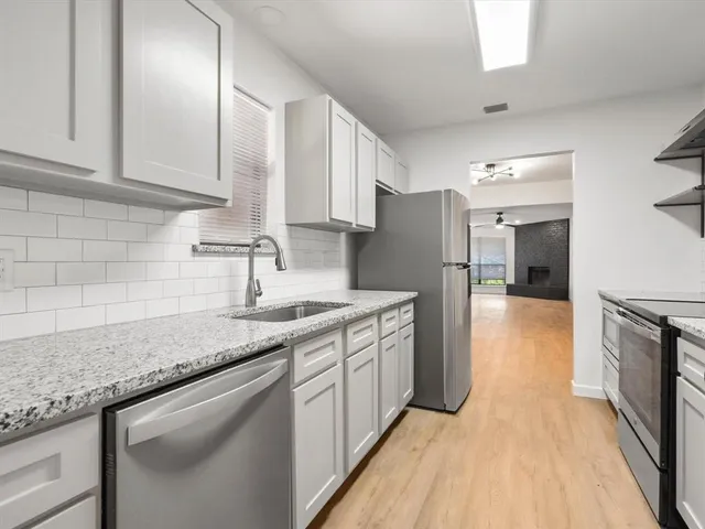 a kitchen with stainless steel appliances granite countertop a sink and a refrigerator