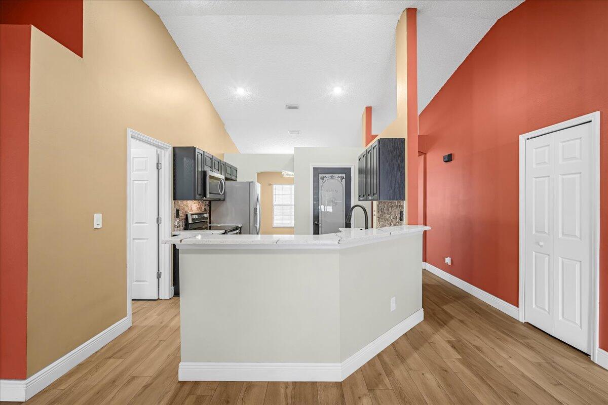 6445 Ainsworth Road Cocoa, FL 32927 - Photo 17 of 31 a living room with stainless steel appliances kitchen island hardwood floor and a ceiling fan