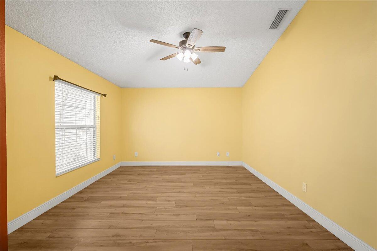 6445 Ainsworth Road Cocoa, FL 32927 - Photo 9 of 31 a view of an empty room with wooden floor and a window