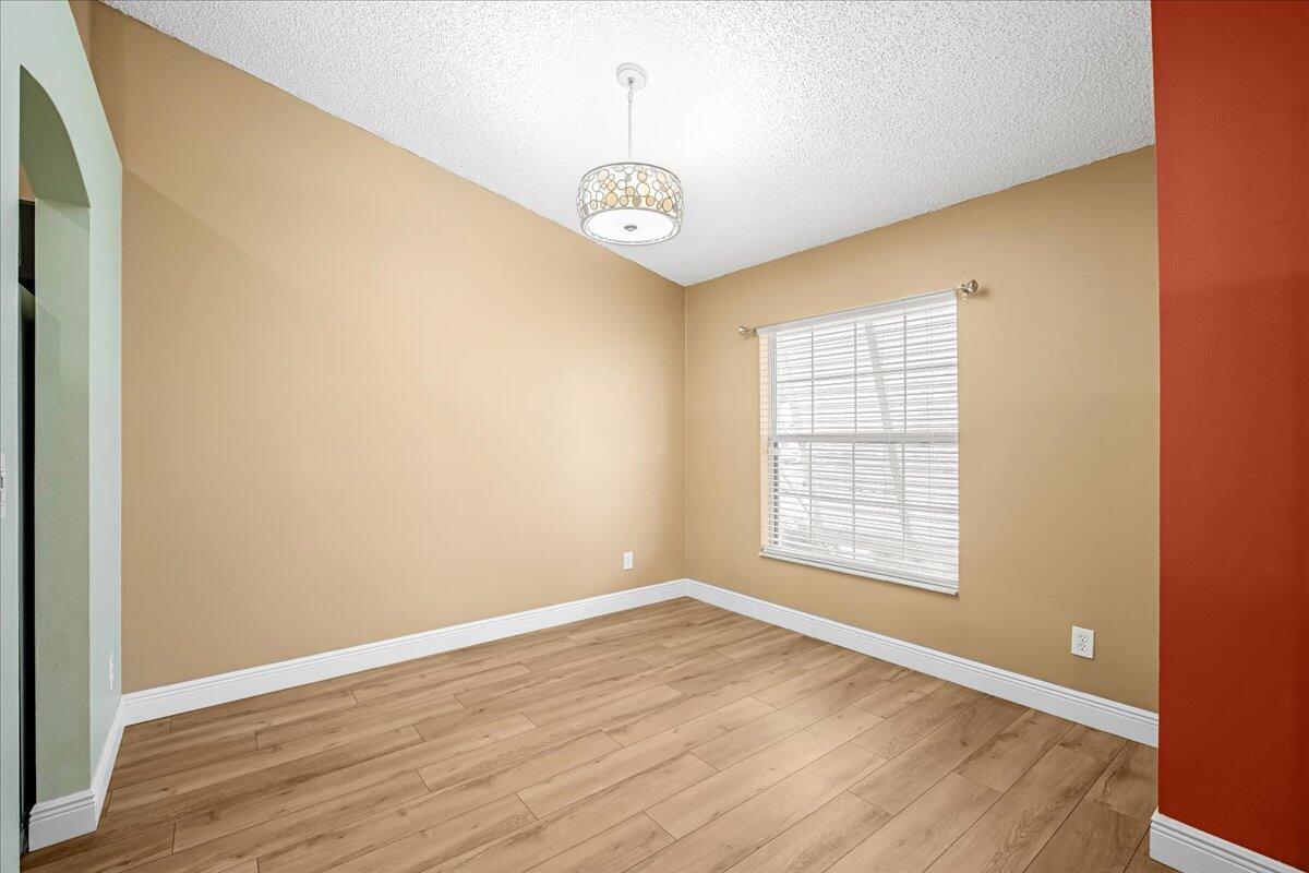 6445 Ainsworth Road Cocoa, FL 32927 - Photo 10 of 31 an empty room with wooden floor chandelier and windows