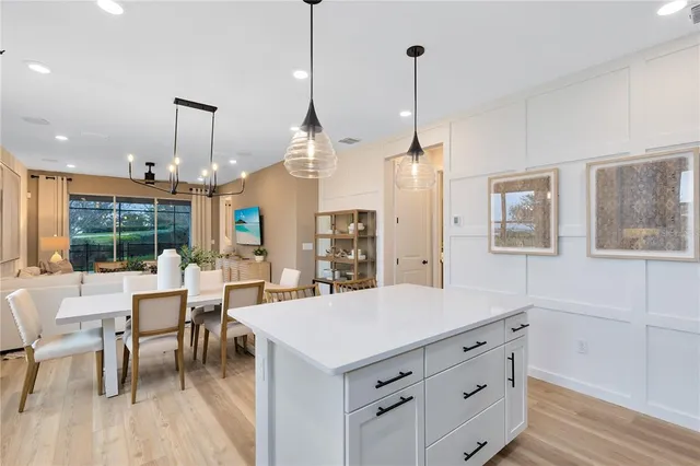 a kitchen with stainless steel appliances a dining table chairs refrigerator and microwave