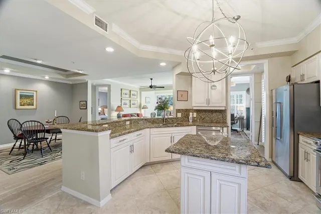 an open kitchen with granite countertop kitchen island stainless steel appliances a dining table and chairs