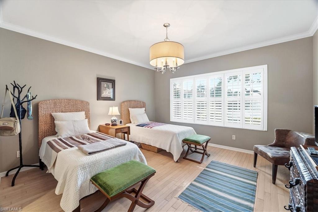 1109 Egrets Walk Circle, Unit 104 Naples, FL 34108 - Photo 9 of 17 a bedroom with two beds and a chandelier