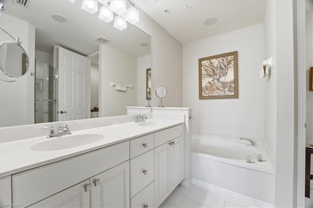 1109 Egrets Walk Circle, Unit 104 Naples, FL 34108 - Photo 10 of 17 a bathroom with a tub a sink and mirror