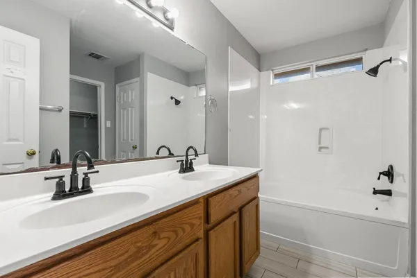 a bathroom with a sink double vanity granite tub shower and a mirror