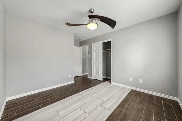 a view of empty room with wooden floor and ceiling fan