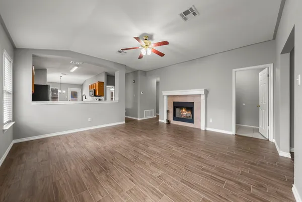 a view of an empty room with window and wooden floor