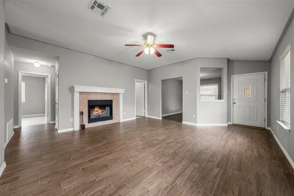 an empty room with wooden floor fireplace and windows