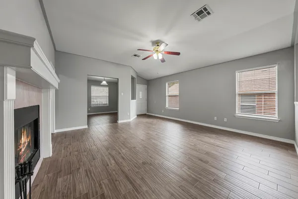 a view of an empty room with a fireplace and wooden floor