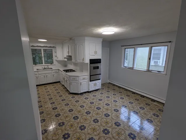a kitchen with granite countertop a sink a stove a window and white cabinets