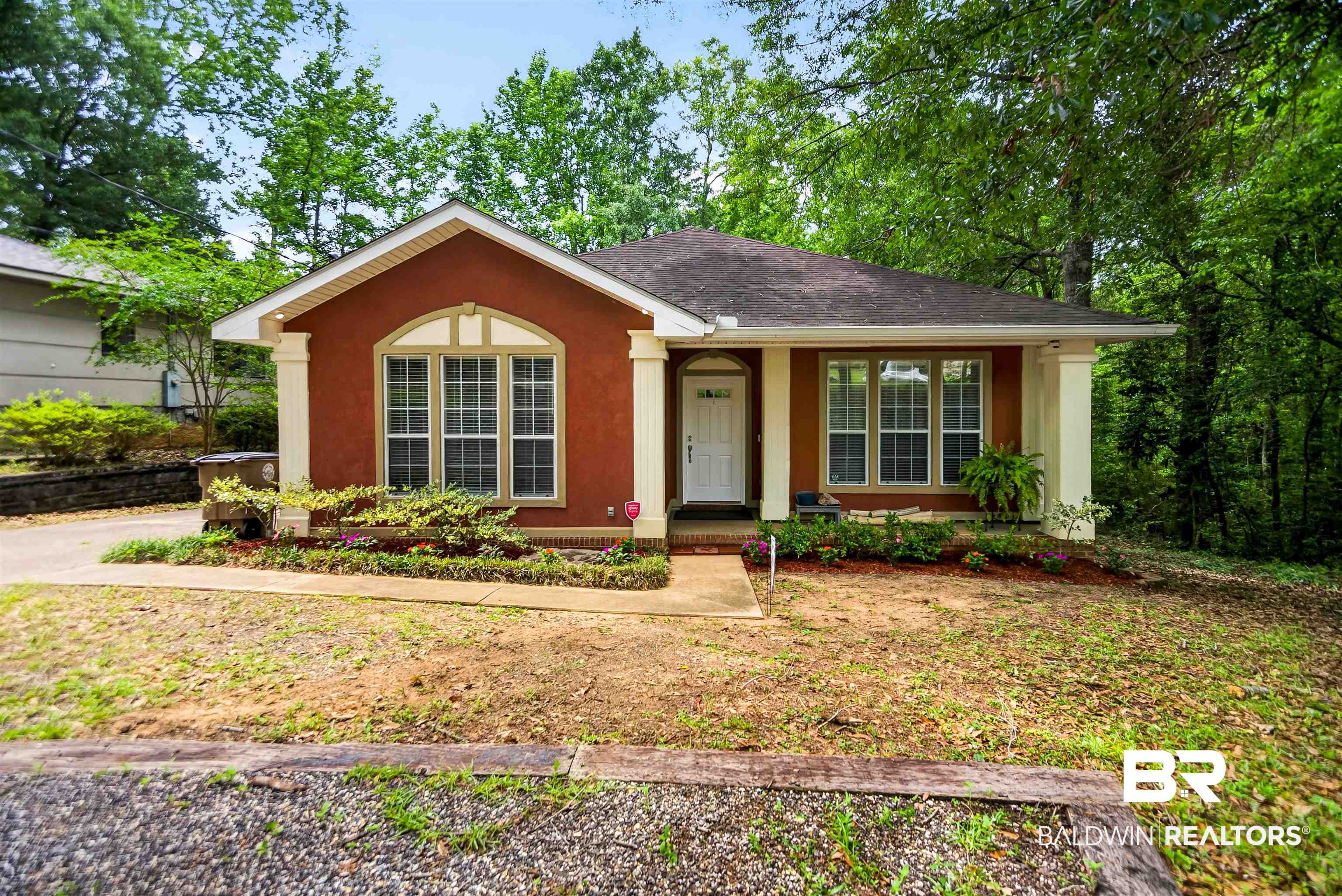 5913 Antoine Road Mobile, AL 36693 - Photo 1 of 33 Stucco exterior featuring a prominent arched window with multi-pane detailing, a covered porch entry, and architectural columns