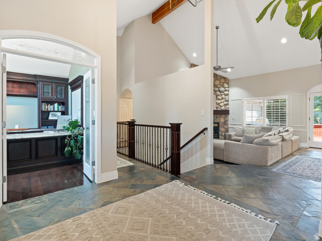 13357 Trail Rider Circle Draper, UT 84020 - Photo 3 of 70 Spacious entry featuring natural stone flooring, an arched doorway, and a wrought iron railing leading to an open living area
