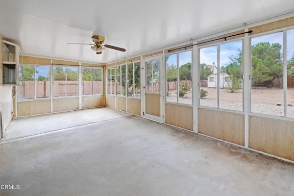 a view of empty room with floor to ceiling window and ceiling fan