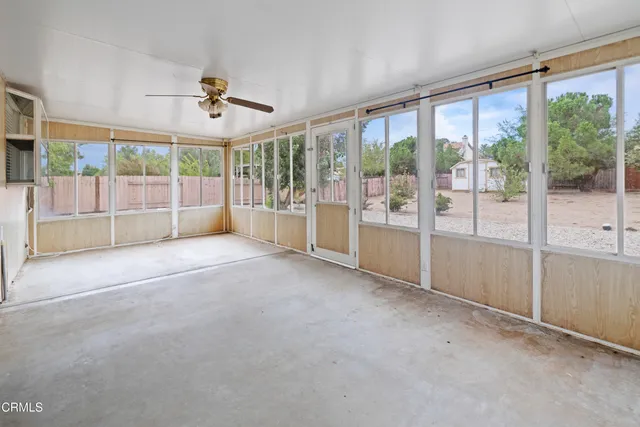a view of empty room with floor to ceiling window and ceiling fan