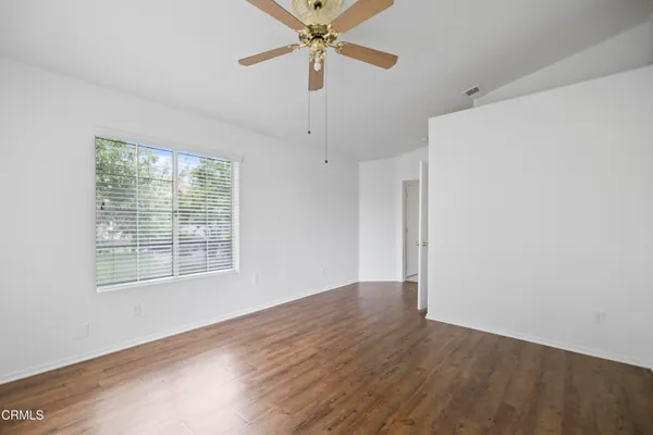 a view of an empty room with a window and wooden floor