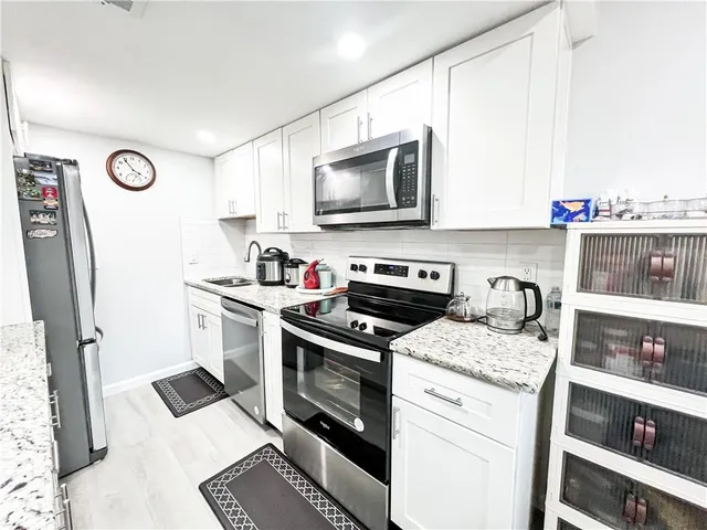 a kitchen with stainless steel appliances granite countertop a stove top oven a sink a dining table and chairs with wooden floor