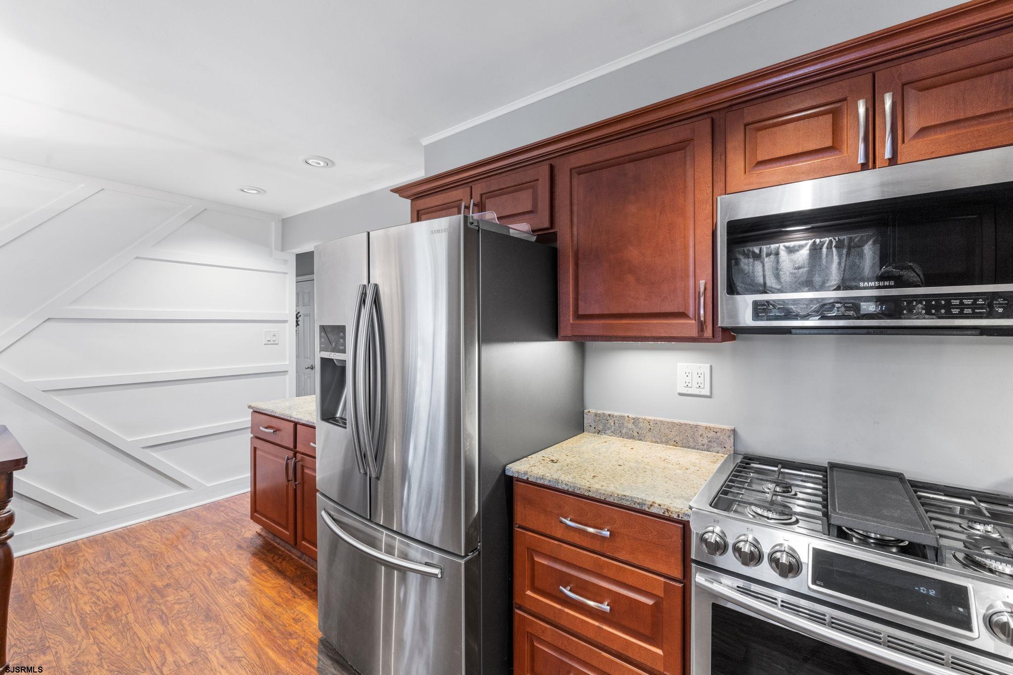 210 Mill Road Absecon, NJ 08201 - Photo 16 of 52 a kitchen with stainless steel appliances granite countertop a refrigerator a stove and a sink with wooden floors