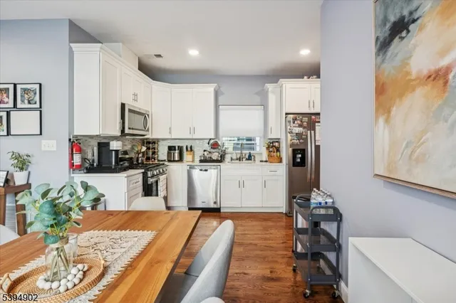 a kitchen with stainless steel appliances kitchen island granite countertop a refrigerator sink and white cabinets