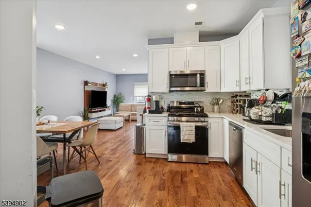 a kitchen with a microwave a stove a sink dishwasher and a refrigerator with wooden floor