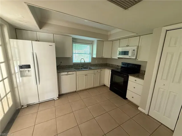 a kitchen with white cabinets a refrigerator a sink and dishwasher