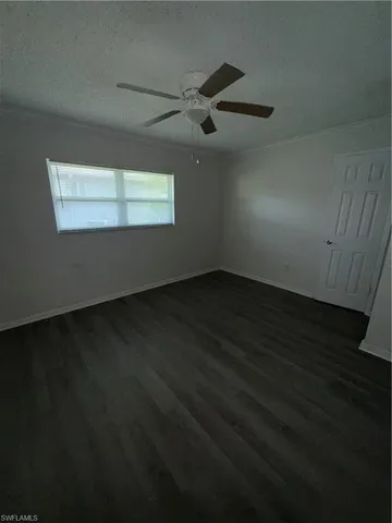 a view of an empty room with wooden floor and a ceiling fan