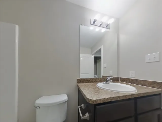 a bathroom with a granite countertop sink and a toilet