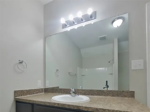 a bathroom with a granite countertop sink and a mirror