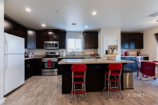 916 South Farragut Street Ridgecrest, CA 93555 - Photo 9 of 30 a kitchen with stainless steel appliances granite countertop a refrigerator a stove a sink dishwasher and a microwave with wooden floor
