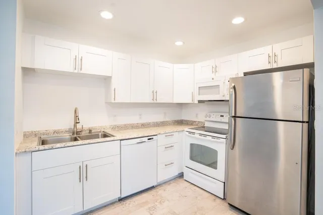 a kitchen with a refrigerator sink and white cabinets
