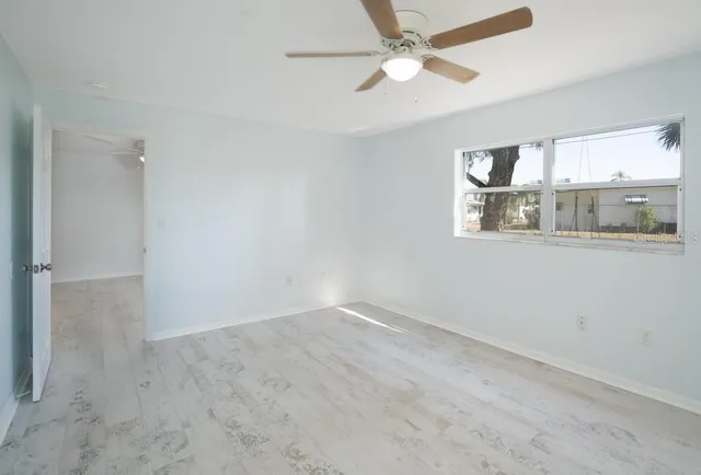 an empty room with windows and fan