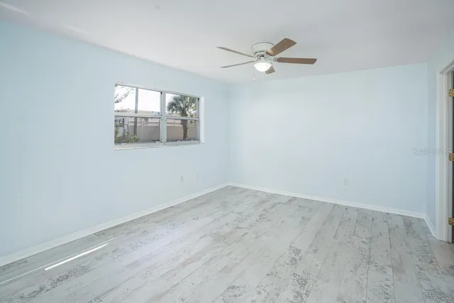 an empty room with a window and a ceiling fan
