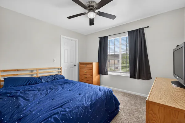 a bed sitting in a bedroom next to a window with pc on the dresser