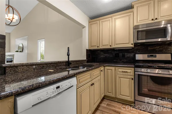 a kitchen with stainless steel appliances granite countertop a stove a sink and a microwave