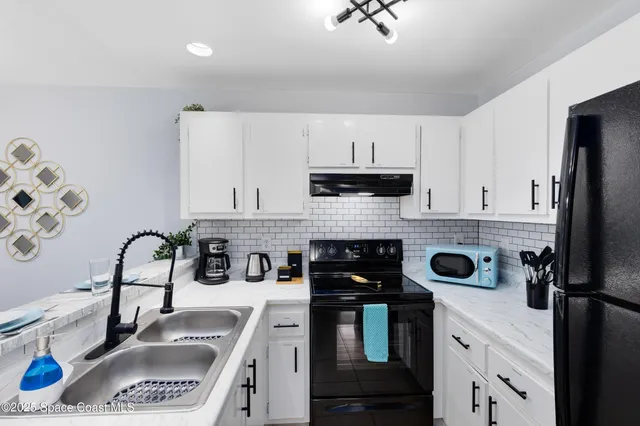 a kitchen with refrigerator a sink a stove and cabinets