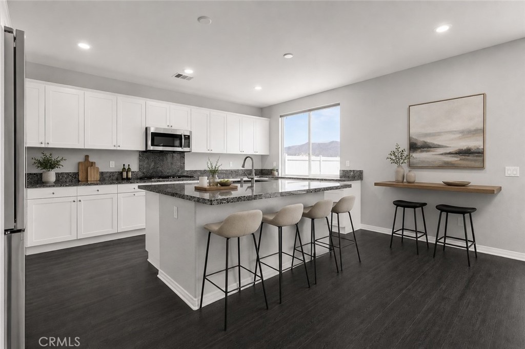 11056 Guffey Ranch Way Corona, CA 92883 - Photo 10 of 61 a kitchen with stainless steel appliances granite countertop a stove a sink a microwave a refrigerator and white cabinets with wooden floor
