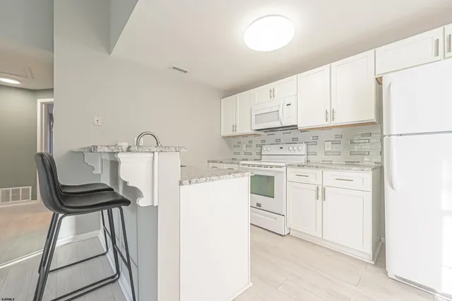 a kitchen with white cabinets and white appliances