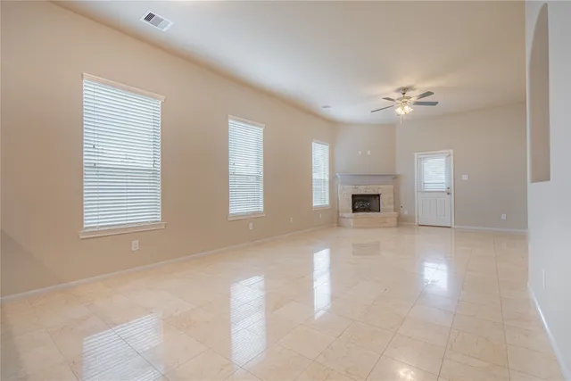a view of a livingroom with a fireplace a ceiling fan and windows