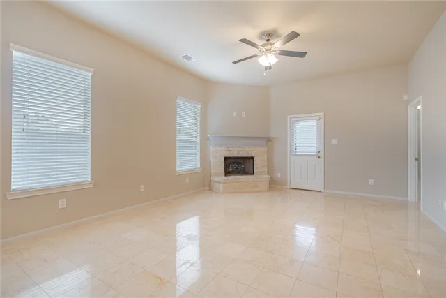 an empty room with chandelier fan and windows