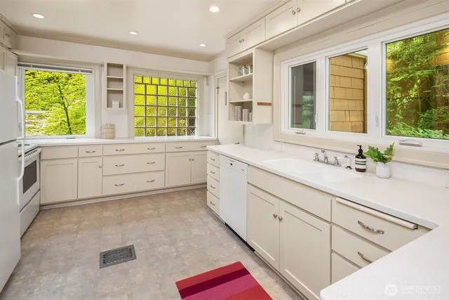 a large white kitchen with granite countertop a white cabinets and a large window