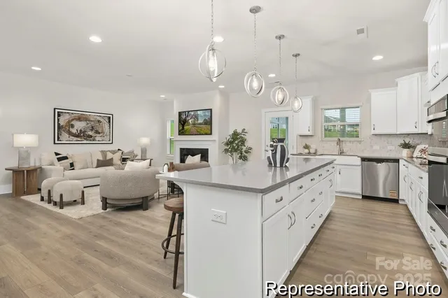 a large white kitchen with a large island oven a stove a chimney a sink and dining table