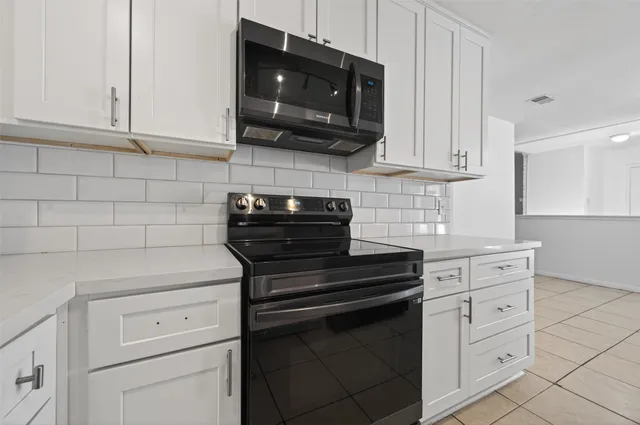 a kitchen with white cabinets and black appliances