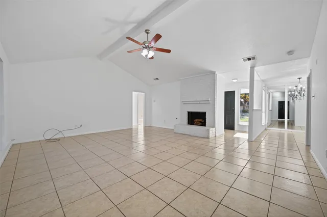 a view of an empty room and chandelier fan