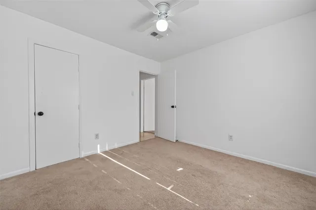an empty room with a ceiling fan and wooden floor