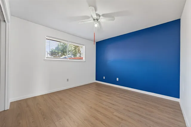 an empty room with wooden floor fan and windows