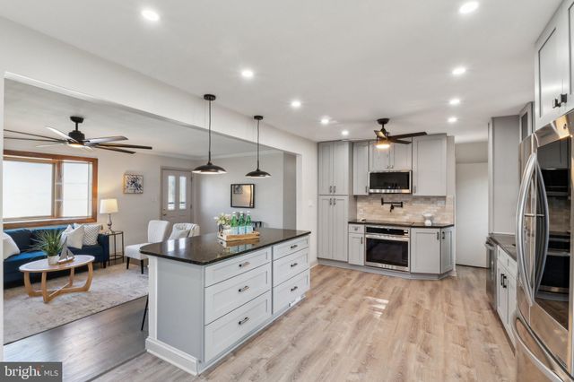 a kitchen with stainless steel appliances kitchen island granite countertop a stove refrigerator and cabinets