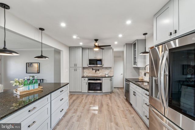 a large kitchen with stainless steel appliances kitchen island a large counter top space a sink stainless steel appliances and cabinets