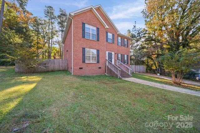 a front view of house with yard and trees in the background