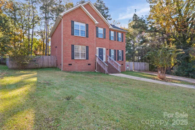 a front view of house with yard and trees in the background