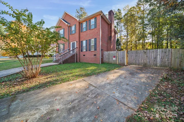 a view of a brick house next to a yard with large trees